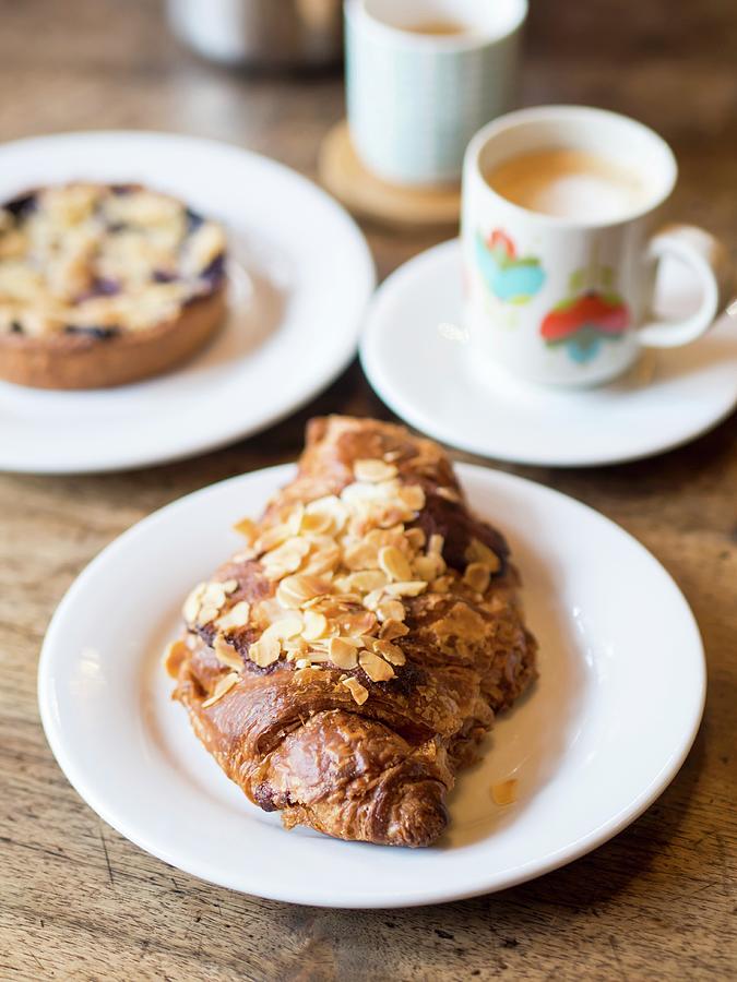 An Almond Croissant Served With Coffee In A Caf In France Photograph by Magdalena Paluchowska