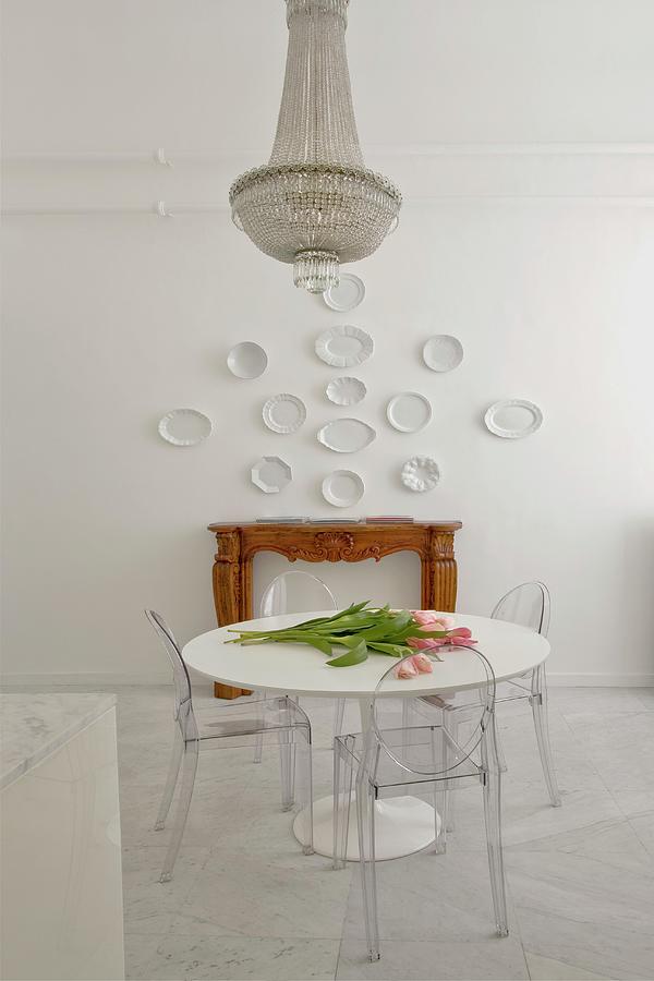 An Antique Chandelier Above A White Table With Transparent Acrylic Glass Chairs On A Marble Floor Photograph by Fabio Lombrici