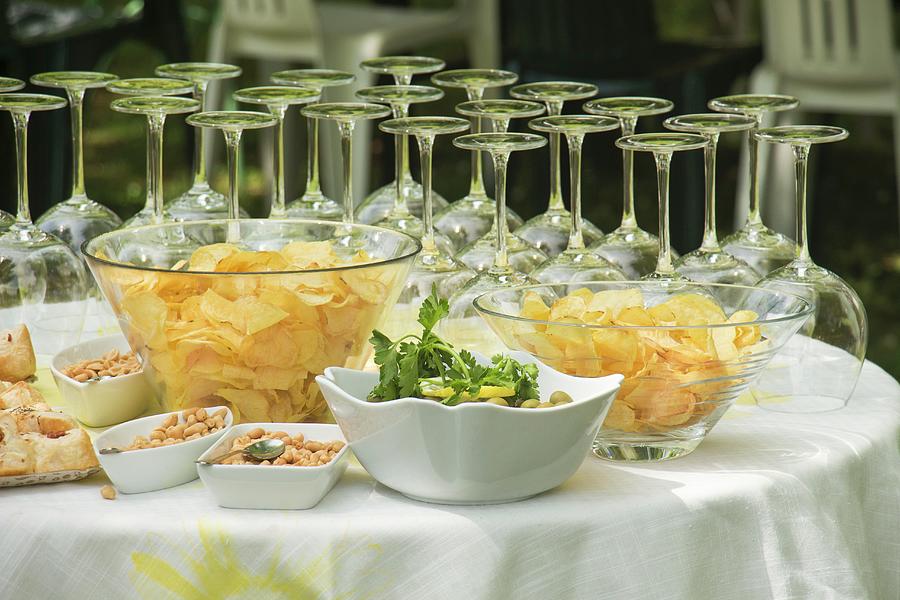An Aperitif Buffet With Wine Glasses, Crisps, Olives And Peanuts Photograph by Alice Del Re