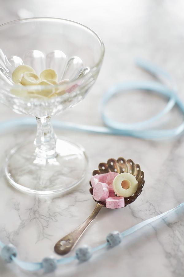 An Arrangement Featuring A Beaded Ribbon And Sweets In A Glass Bowl And On A Silver Spoon Photograph by Alicja Koll