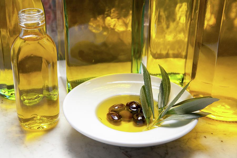 An Arrangement Featuring A Bottle Of Olive Oil And Olives In Oil With An Olive Sprig On A White Plate Photograph by Riccardobruni