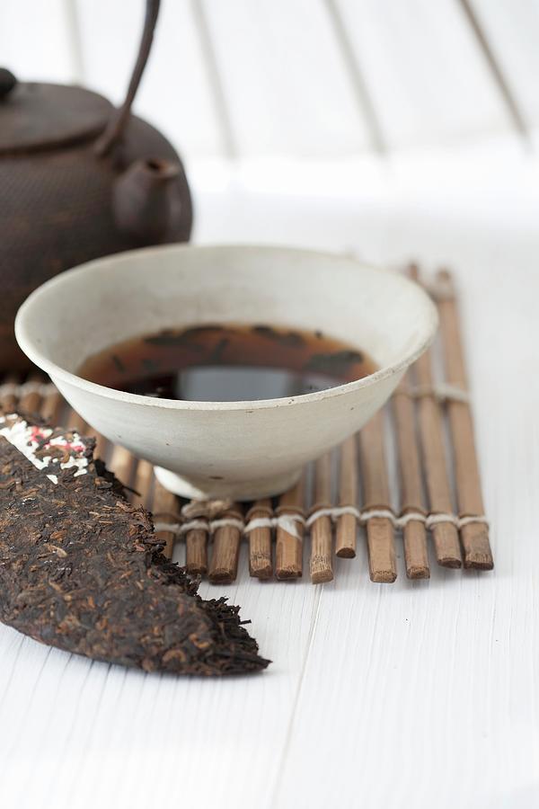 An Arrangement Featuring A Tea Brick And Brewed Pu-ehr Tea In A Tea Bowl Photograph by Martina Schindler