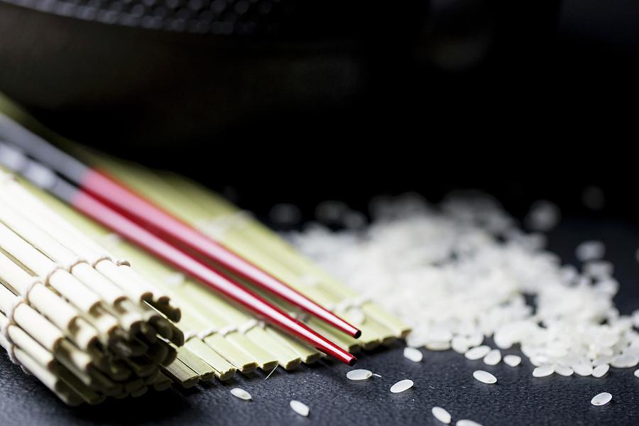 An Arrangement Featuring Chopsticks, A Bamboo Mat And Rice asia Photograph by Nicole Godt