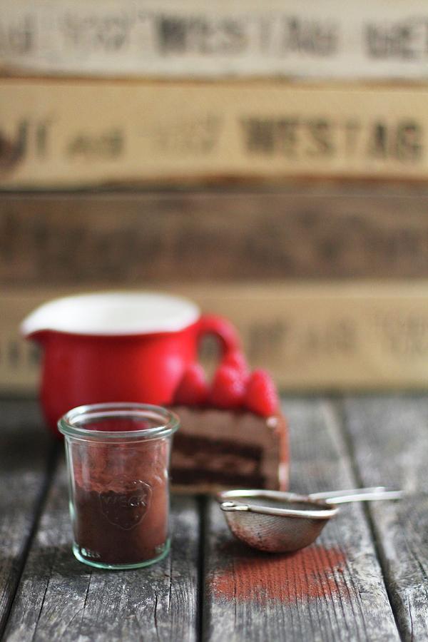 An Arrangement Of Cocoa Powder In A Glass Jar And A Sieve In Front Of A Slice Of Cake And A Jug Of Milk Photograph by Sylvia E.k Photography