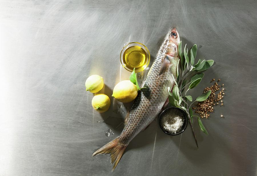 An Arrangement Of Fish, Lemons, Olive Oil, Sage And Spices Photograph by Danny Lerner