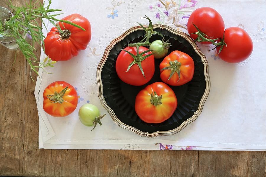 An Arrangement Of Home-grown Vine Tomatoes On An Embroidered Tablecloth Photograph by Regina Hippel
