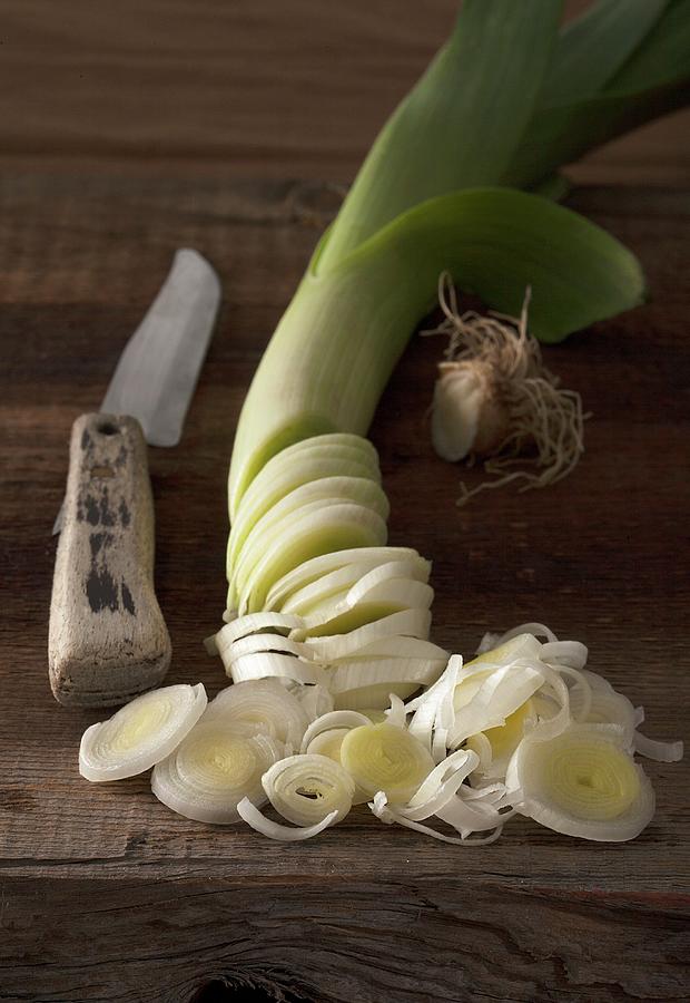An Arrangement Of Leek And An Old Vegetable Knife On A Rustic Wooden Table Photograph by Blueberrystudio