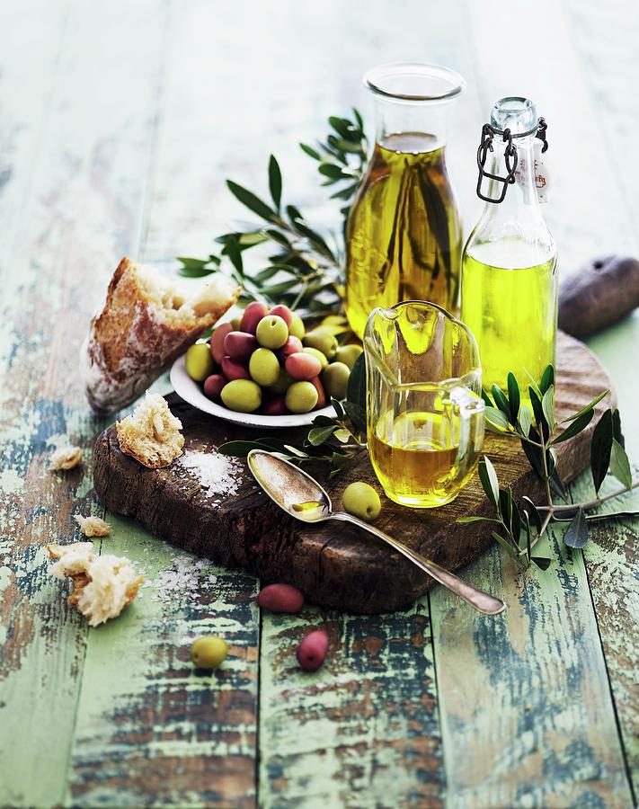 An Arrangement Of Oils With Olive Sprigs, Olives And Bread Photograph by Mikkel Adsbl