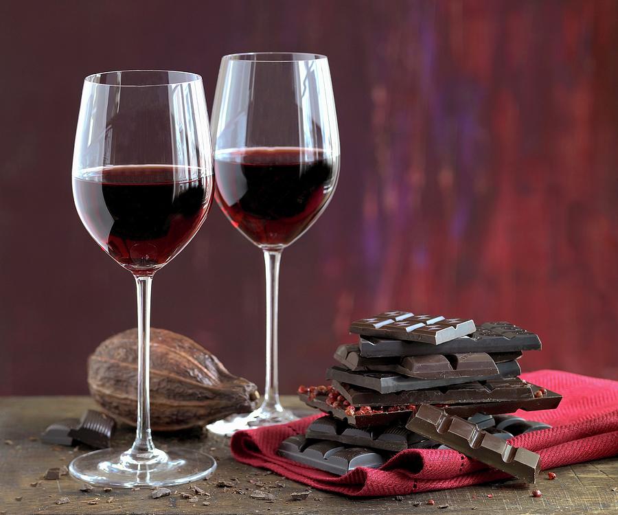 An Arrangement Of Red Wine Glasses, Cocoa Beans And A Stack Of Chocolate Photograph by Jalag / Bernhardi Fr Prinz