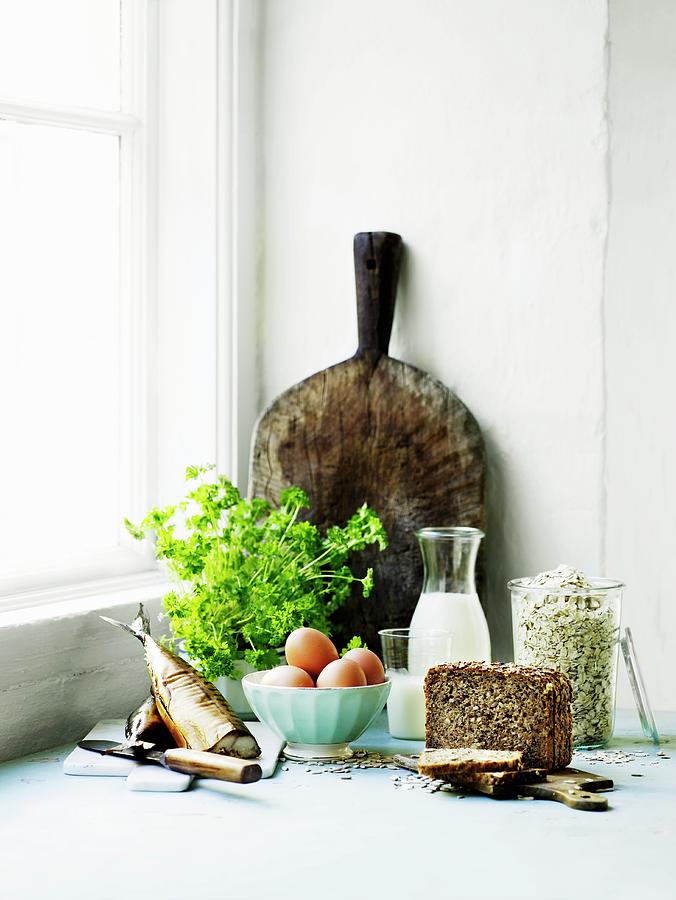 An Arrangement Of Smoked Fish, A Bunch Of Parsley, Bread And A Rustic Wooden Chopping Board Photograph by Mikkel Adsbl