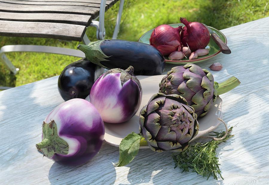 An Arrangement Of Vegetables, Artichokes, Onions And Garlic On A Garden Table Photograph by Peter Garten