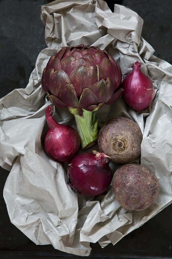 An Arrangement Of Vegetables Featuring Artichoke, Red Onions And Beetroot On Piece Of Paper Photograph by Catja Vedder