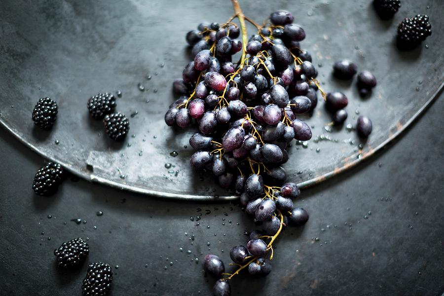 An Arrangement With Red Grapes And Blackberries On An Old Metal Surface Photograph by Sabine Lscher