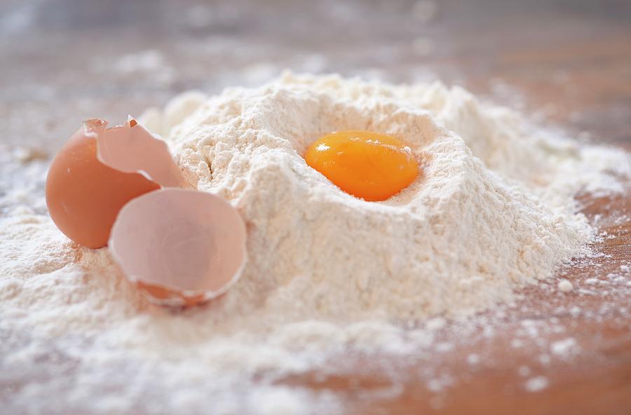 An Egg Yolk And An Eggshell In Flour On A Wooden Slab Photograph by Foodografix