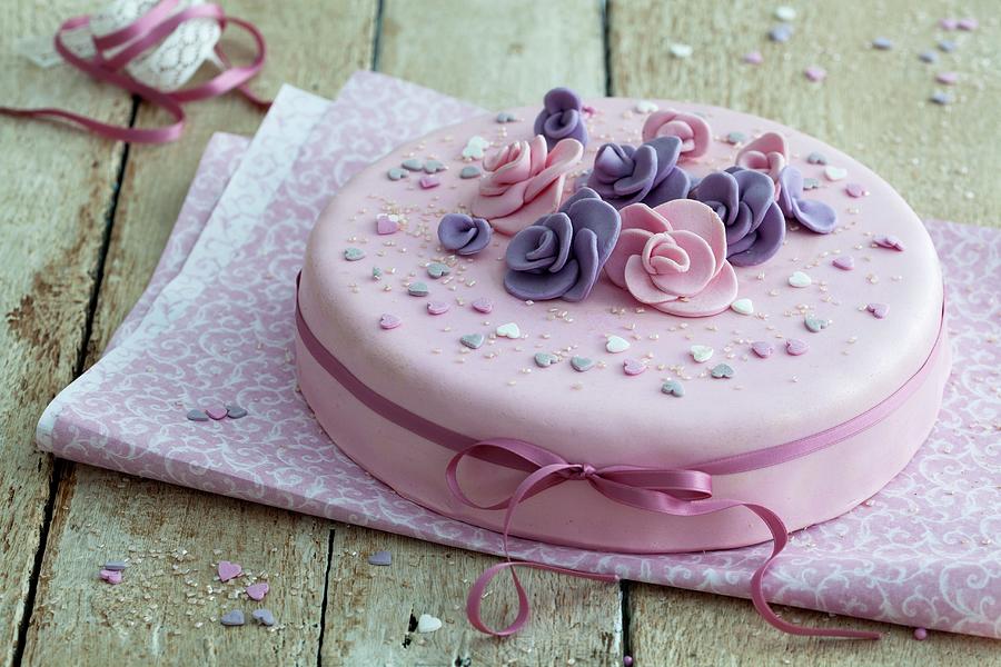 An Elegant Birthday Cake In Pink With Fondant Flowers And A Stain Ribbon On A Rustic Wooden Table Photograph by Blueberrystudio