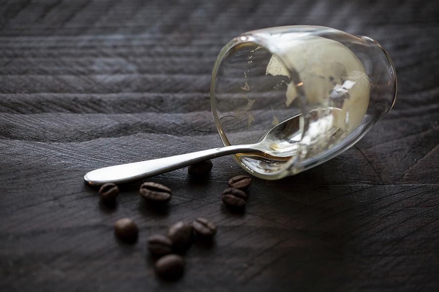 An Empty Espresso Glass With A Spoon And Coffee Beans On A Wooden Table Photograph by Nicole Godt
