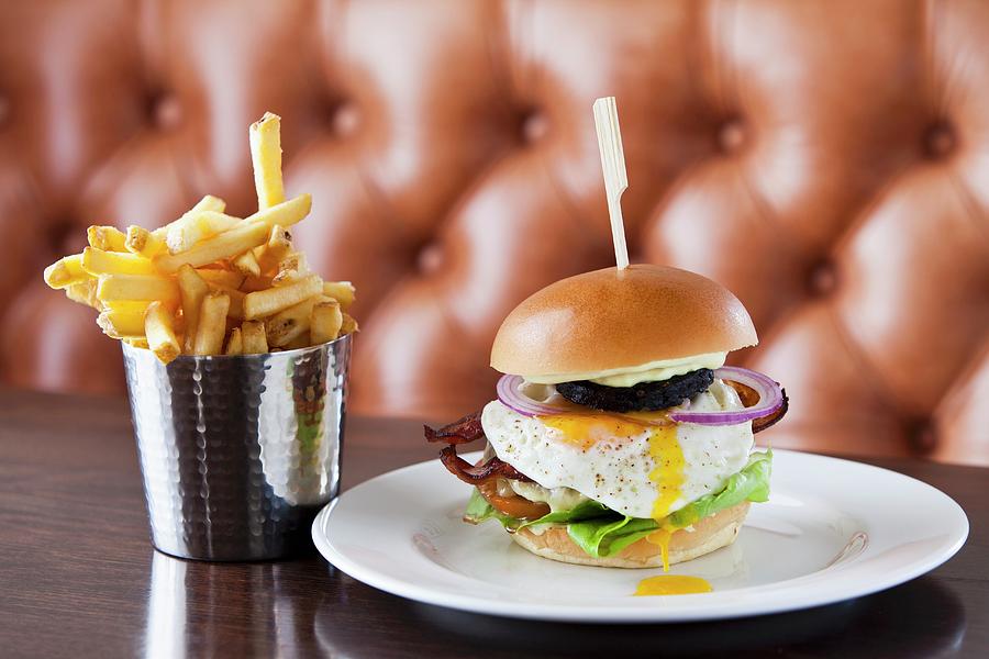An English Burger With A Fried Egg And Chips On A Table In A Restaurant Photograph by Jalag / Sren Gammelmark