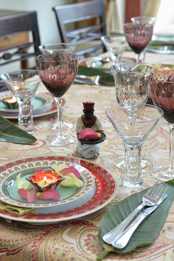 An Exotically Laid Table With Crystal Glasses, Banana Leaves, Tea Lights And Petals Photograph by Great Stock!