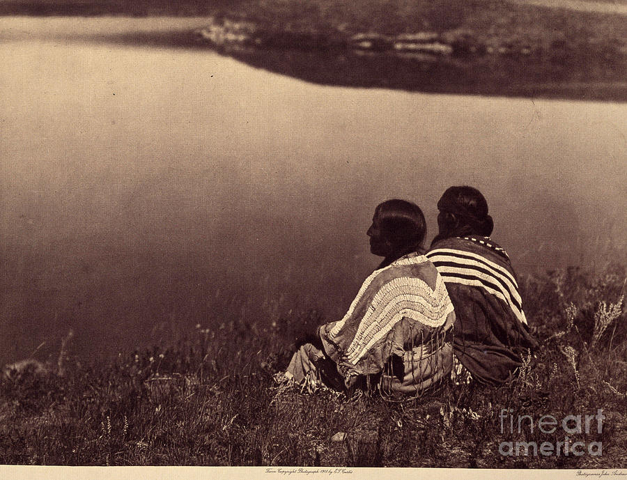 An Idle Hour - A Moment Of Tranquility: Piegan Indians Sitting On The Edge Of A Body Of Water. Photo Taken From Volume 6 Of The Encyclopedia Published By Edward S. Curtis Photograph by Edward Sheriff Curtis