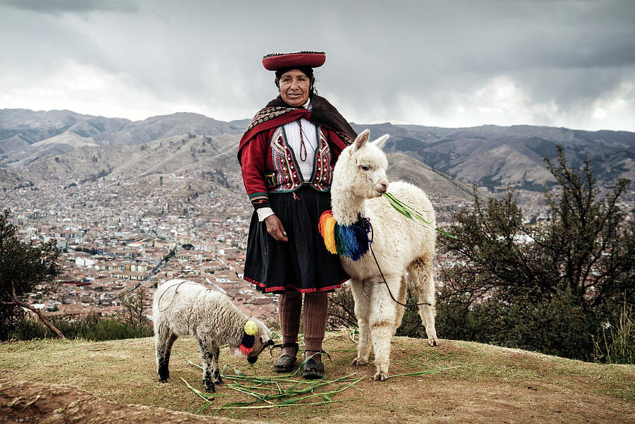 Animal Photograph - An indingeous Quechua woman with a baby alpaca and a sheep near Cusco, Peru by Kamran Ali