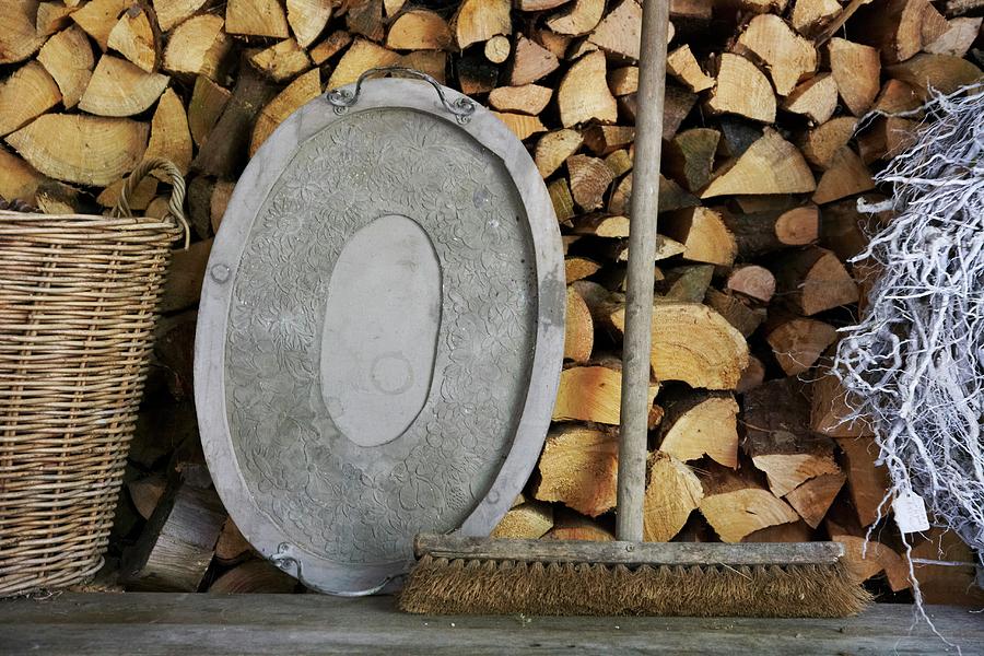 An Old Broom And A Metal Tray On A Wooden Bench In Front Of A Wood Pile Photograph by Charlotte Murphy