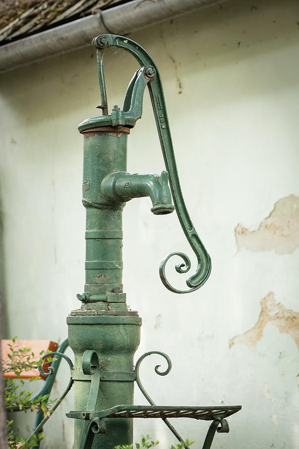 An Old Green Garden Fountain Pump In Front Of An Old House Photograph