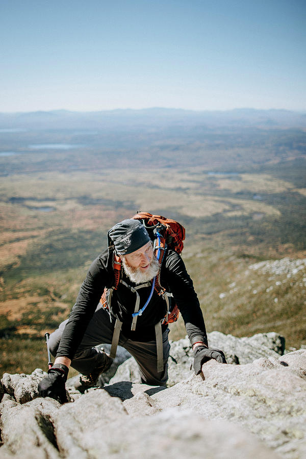 An Older Male Hiker Climbs Hand Over Hand On Mount Katahdin In Maine ...