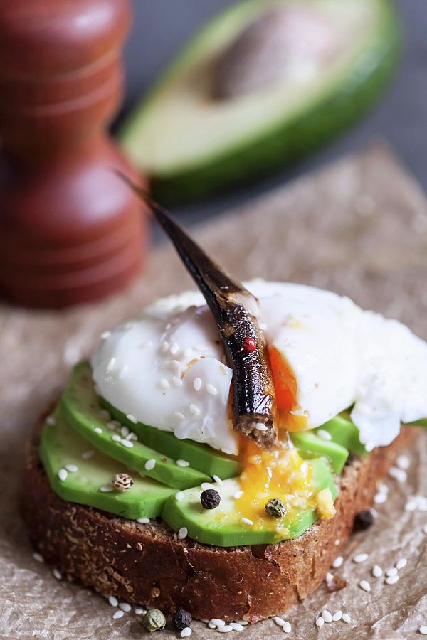 An Open Sandwich With Avocado, Poached Egg And An Anchovy Photograph by Sonya Baby