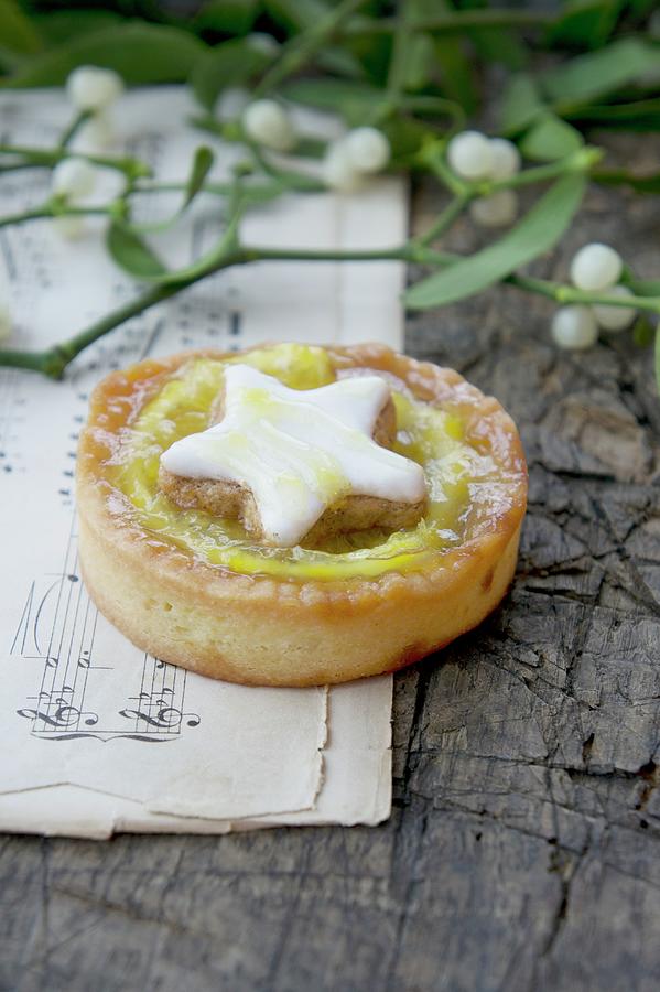 An Orange Tartlet Decorated With A Cinnamon Star With Mistletoe Sprigs On A Piece Of Sheet Music Photograph by Martina Schindler