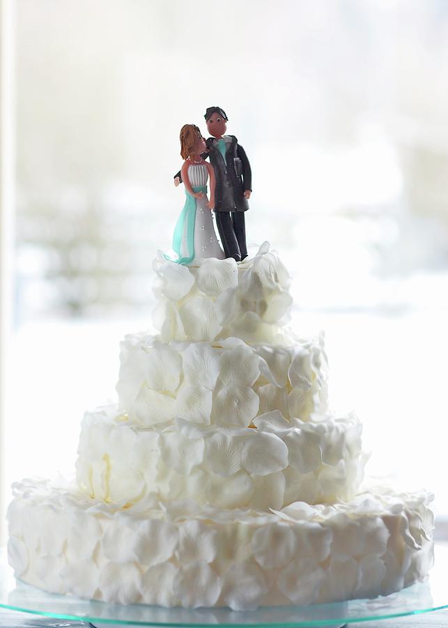 An Original Wedding Cake Decorated With White Rose Petals And A Bridal Couple In Marzipan Photograph by Fotos Mit Geschmack