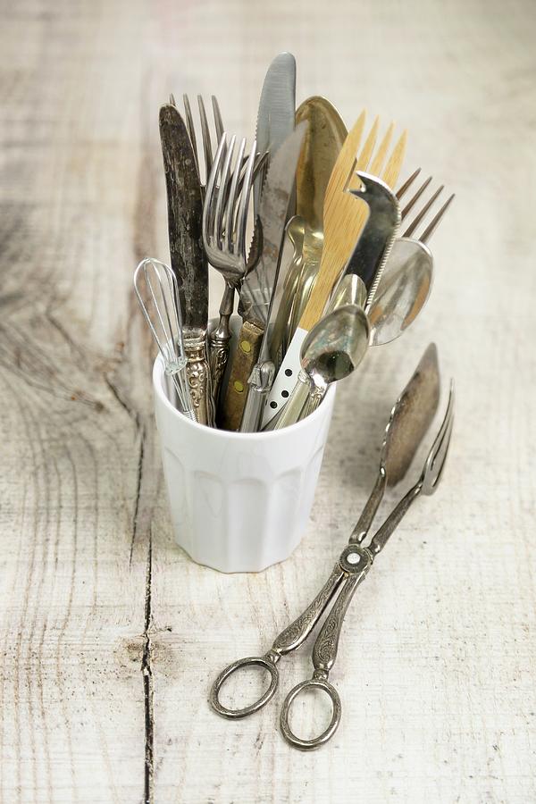 Antique Cutlery In A Mug, With A Pair Of Tongs Photograph by Claudia Gargioni