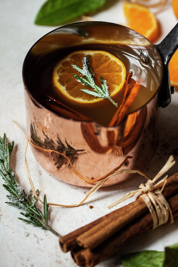Apple Cider Heated In An Antique Copper Pot, With Oranges With Leaves, Orange Slices, Cinnamon Sticks And Sugared Rosemary Photograph by Ryla Campbell