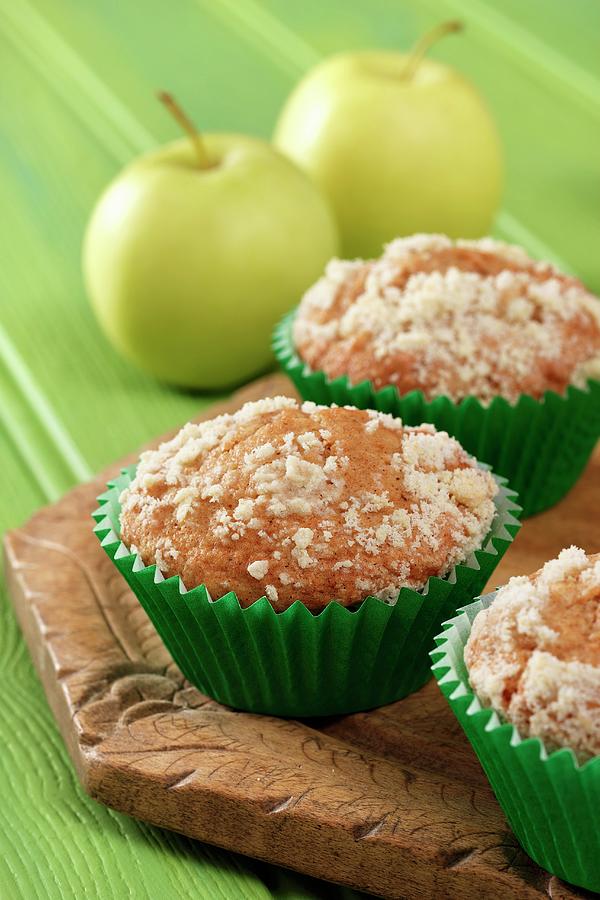 Apple Streusel Muffins On A Wooden Board With Yellow Apples All Sitting On A Green Background. Photograph by Stuart Macgregor