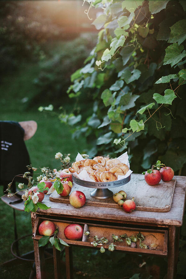 Apples And Baked Apple Rings On A Vintage Wooden Table In A Garden Photograph by Giedre Barauskiene