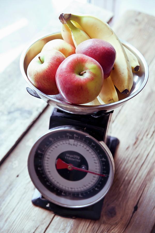 Apples And Bananas On A Pair Of Kitchen Scales Photograph by George Blomfield