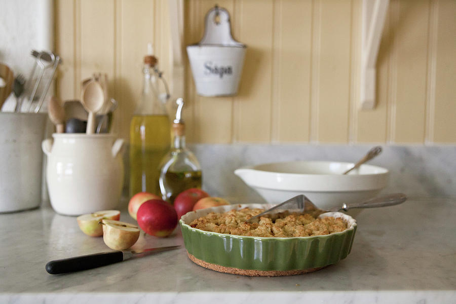 Apples And Pie In Dish On Marble Kitchen Worksurface Photograph by Camilla Isaksson