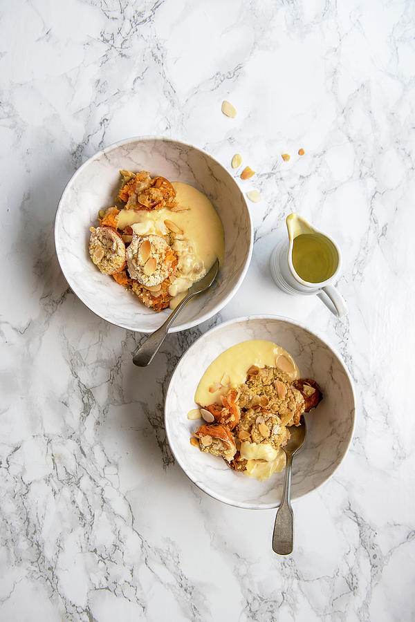 Apricot And Almond Crumble In Serving Bowls With Custard Photograph by Magdalena Hendey