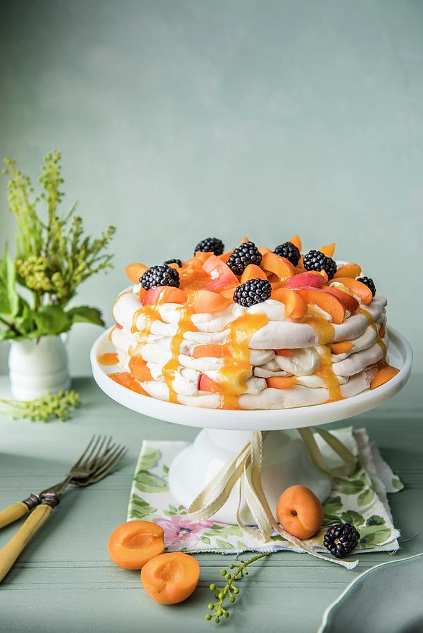 Apricot Pavlova With Apricot Sauce And Blackberries On A White Cake Stand Photograph by Magdalena Hendey