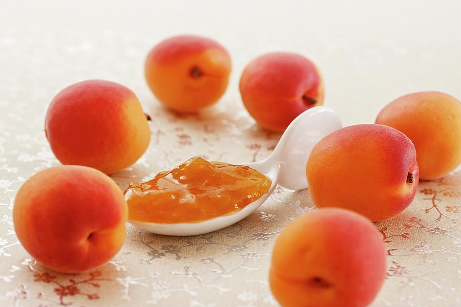 Apricots And A Spoonful Of Jam On A Shimmering Waxed Tablecloth Photograph by Petr Gross