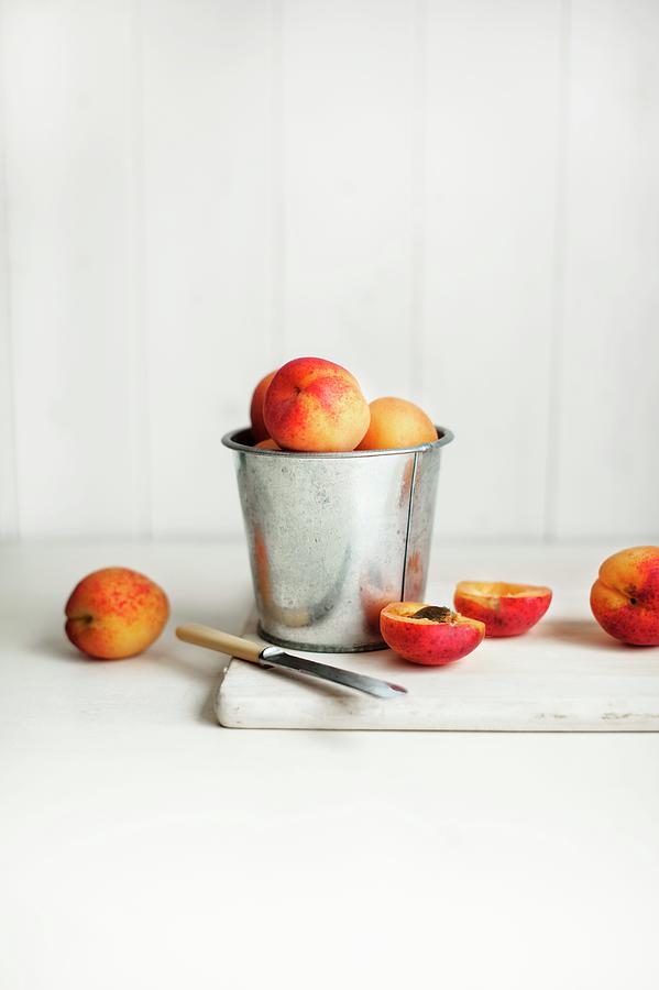 Apricots In A Metal Container And Next To It, One Halved Photograph by Magdalena Hendey
