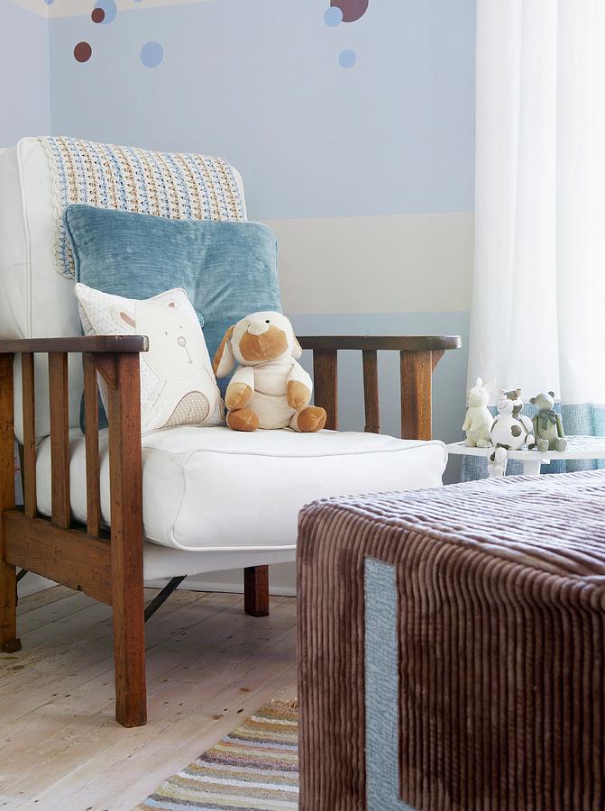 Armchair With Cushions Against Wall Painted Pale Blue And White And Large, Cubic Pouffe With Brown Corduroy Cover In Corner Of Nursery With Various Soft Toys Decorating The Pleasant Room Photograph by Great Stock!