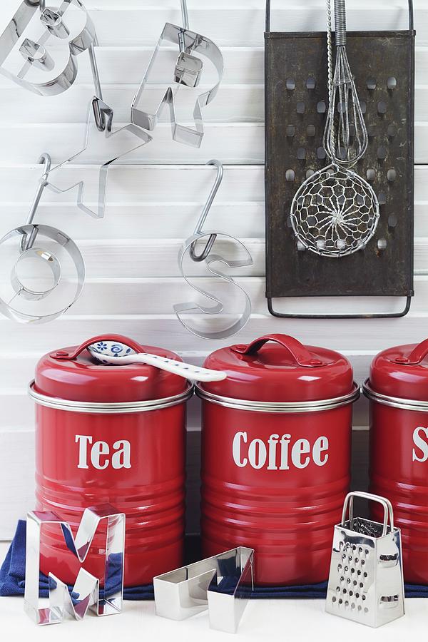Arrangement Of Red Tea And Coffee Storage Jars, Letter-shaped Pastry Cutters And Grater In Kitchen Photograph by Franziska Taube
