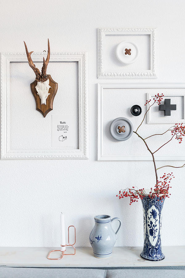Arrangement Of White Picture Frames And Hunting Trophies Above Two Vases Photograph by Studio Lumino