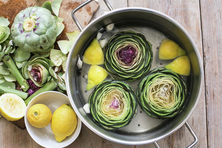 Artichokes With Water, Lemon And Garlic In A Pot Photograph by Sabine Steffens