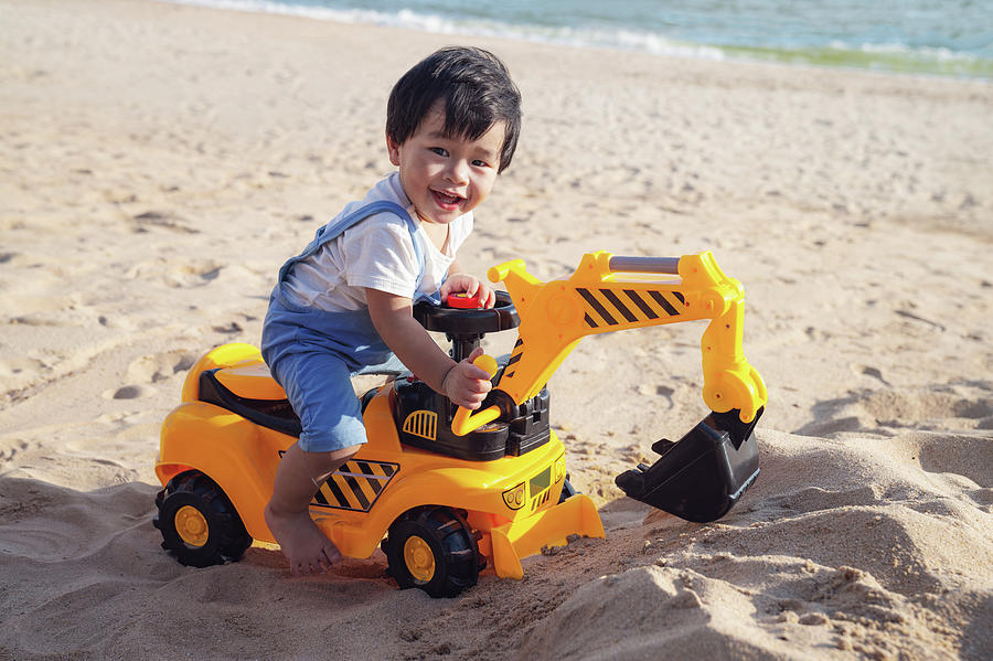 Asian boy play a toy of excavator with a sand Photograph by Anek Suwannaphoom