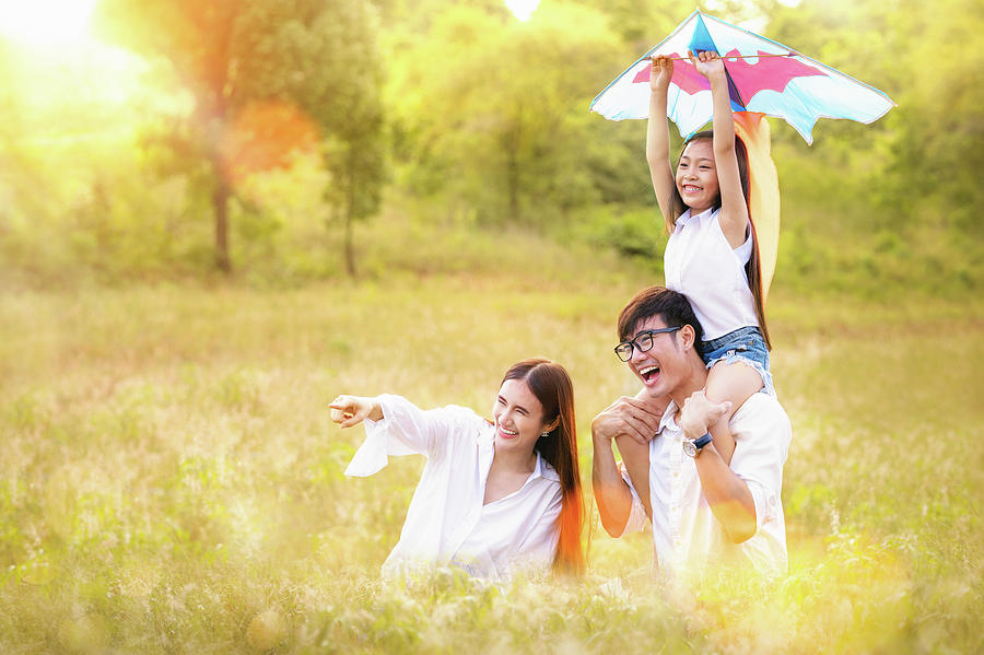 Asian family father, mother and daughter play ta kite in the out by Anek Suwannaphoom Asian family father, mother and daughter play ta kite in the out by Anek Suwannaphoom