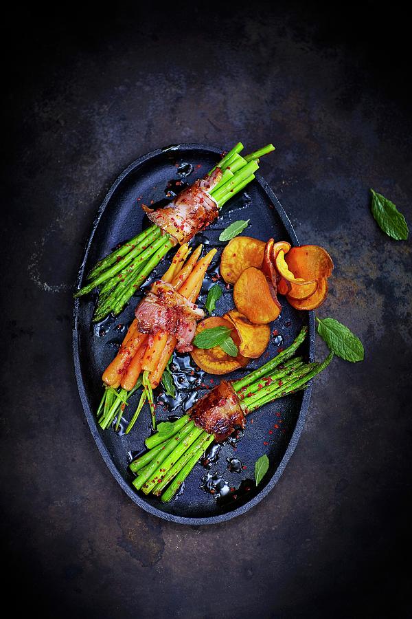 Asparagus And Carrots Wrapped In Bacon With Vegetable Crisps Photograph by Kai Schwabe