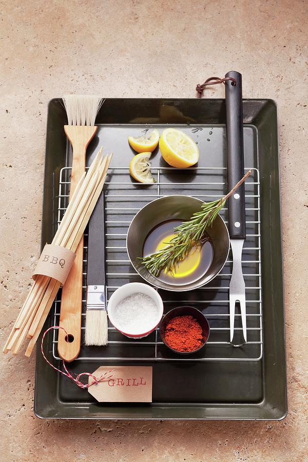 Assorted Barbecue Utensils, Seasonings, Lemons And Olive Oil On A Barbecue Grill Photograph by Eising Studio - Food Photo & Video