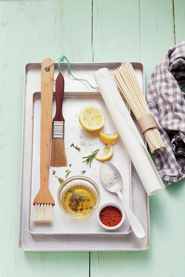 Assorted Barbecue Utensils, Seasonings, Lemons And Olive Oil On A Grill Pan Photograph by Foodcollection