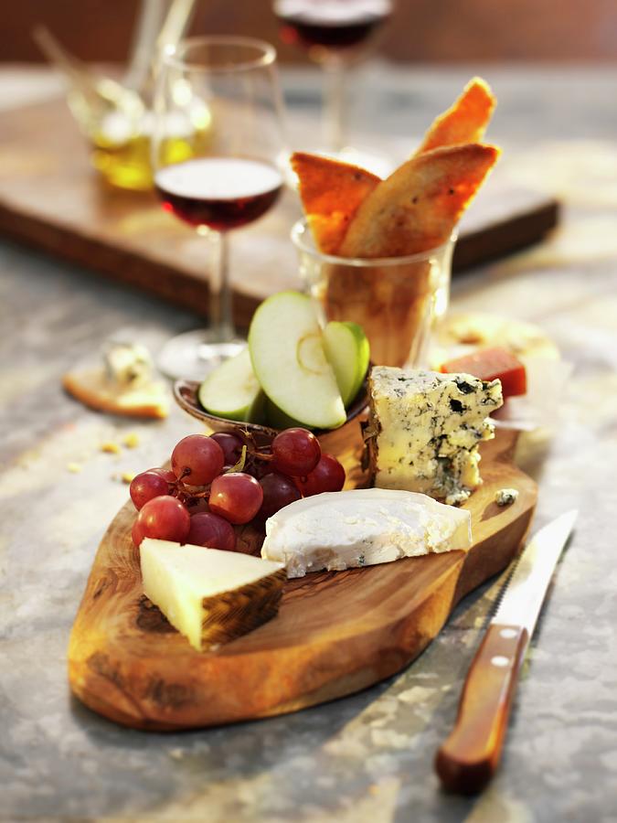 Assorted Cheese With Grapes On Bamboo Board Photograph by Ian Garlick